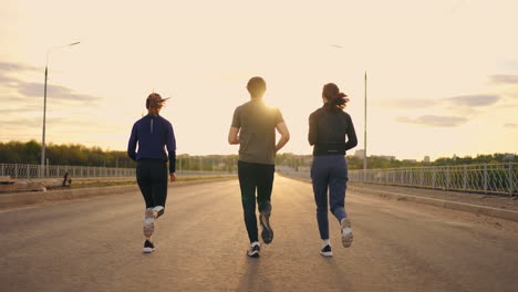 Morgenjoggen-Am-Stadtrand,-Drei-Personen-Laufen-Zusammen,-Rückansicht-Von-Zwei-Frauen-Und-Einem-Mann